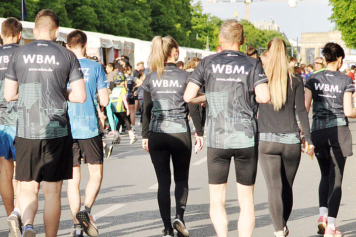 Eine Gruppe Laufende in Firmentrikots der WBM, die an einem Laufevent in Berlin teilnehmen.