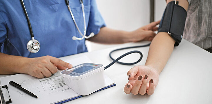 medizinische Fachkraft misst Blutdruck bei Patientem