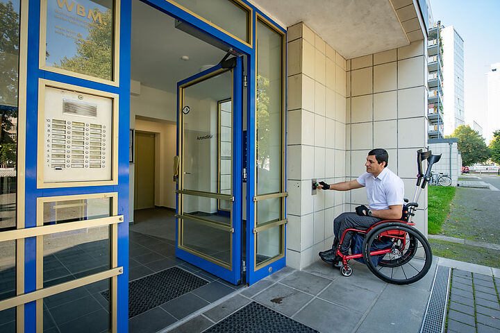 Außenansicht eines Hausengangs in der Karl-Marx-Allee nach barrierefreier Sanierung mit einem Rollstuhlfahrer