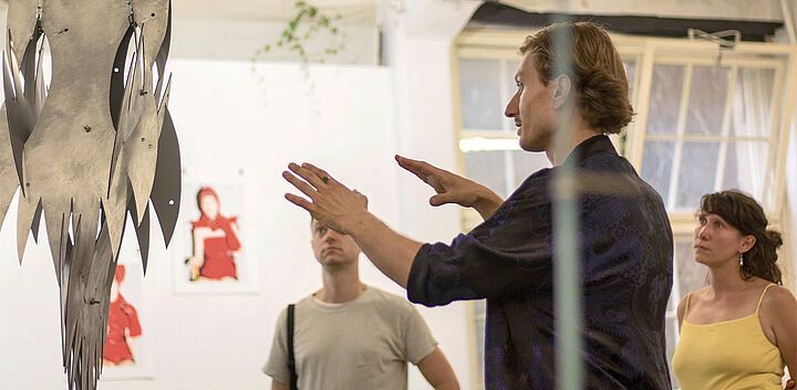 Mann erläutert Gästen Teile der Ausstellung