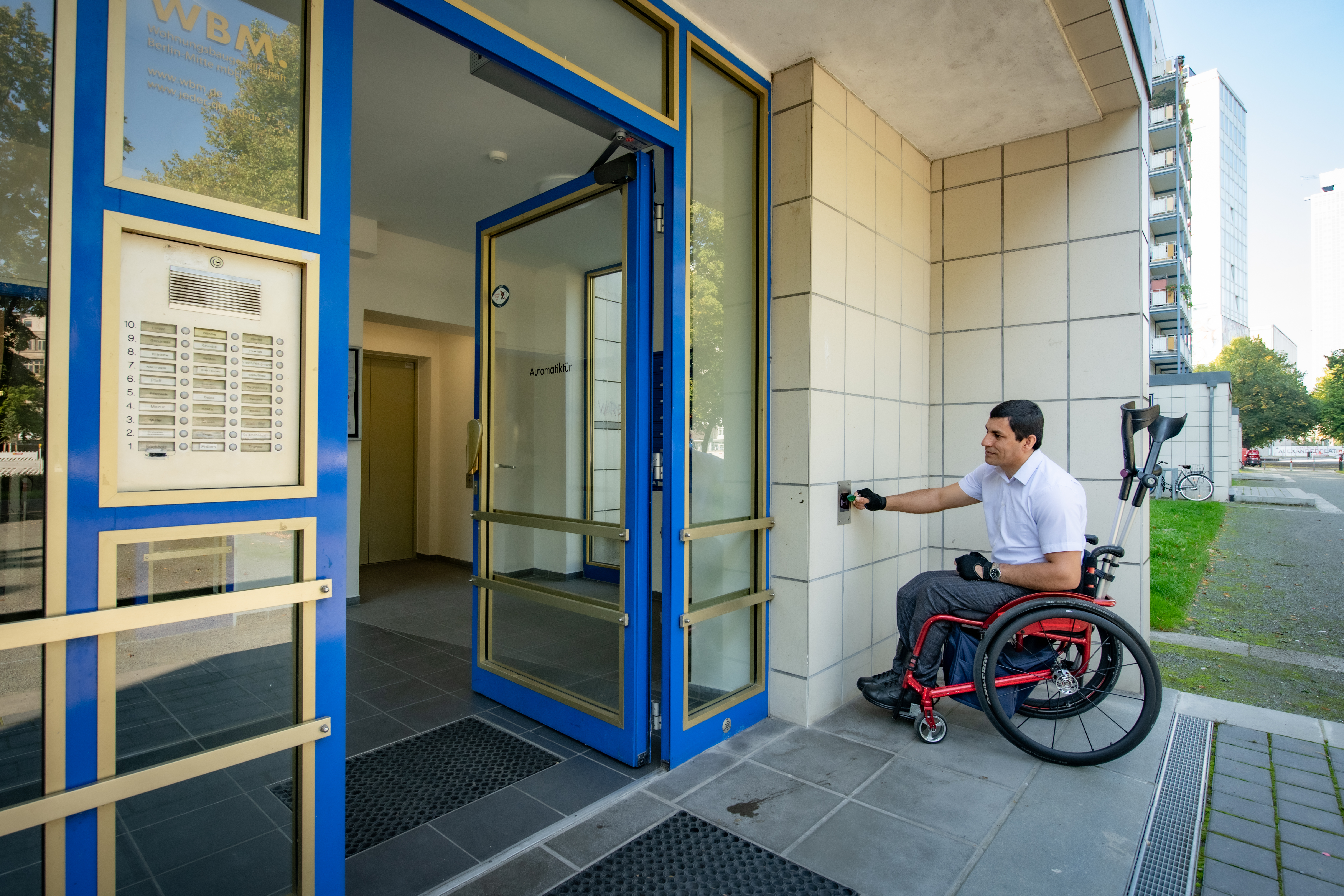 Außenansicht eines Hausengangs in der Karl-Marx-Allee nach barrierefreier Sanierung mit einem Rollstuhlfahrer