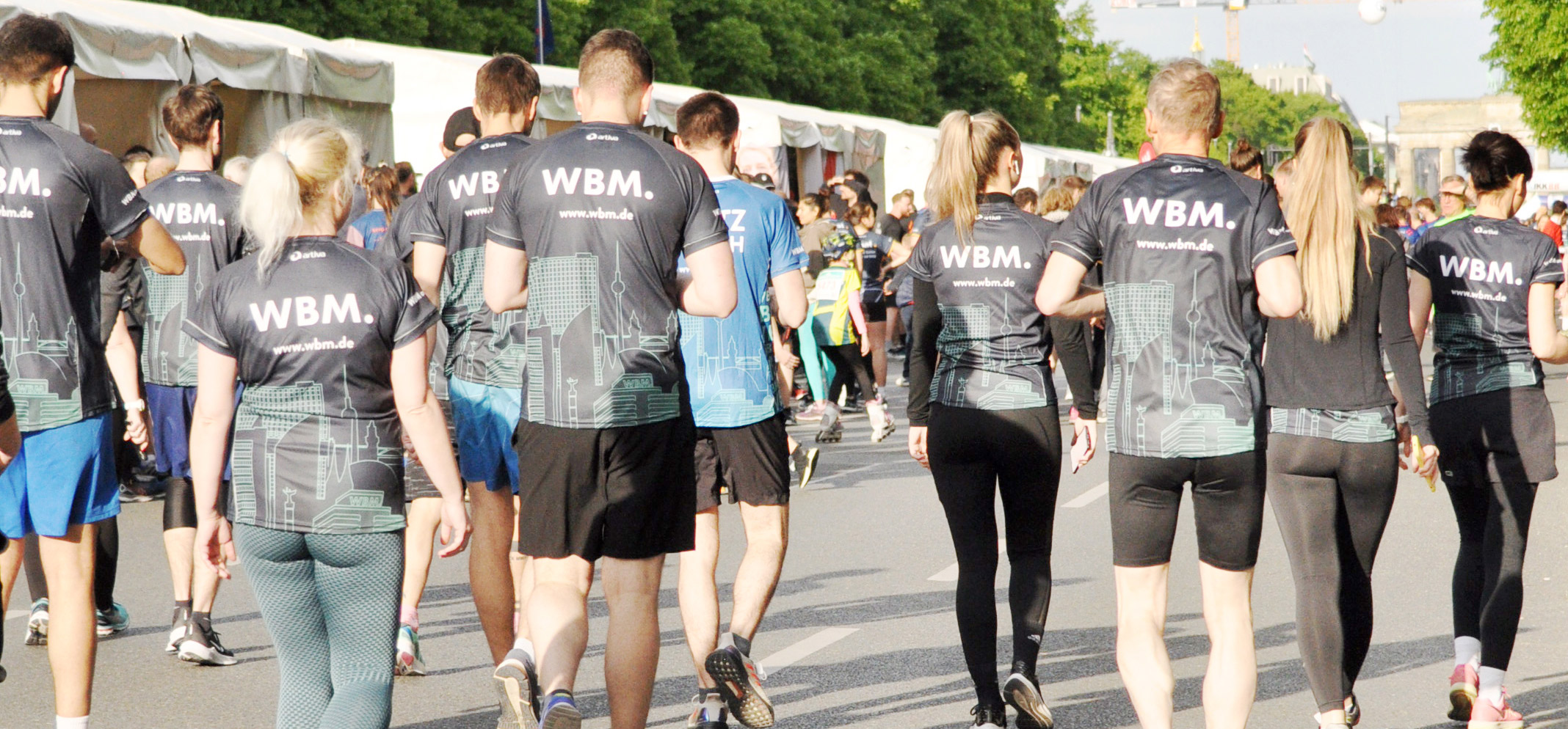 Eine Gruppe Laufender mit Firmentrikots der WBM, die an einem Laufevent in Berlin teilnehmen.